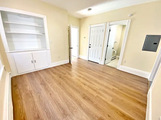 a view of an empty room with wooden floor and a window