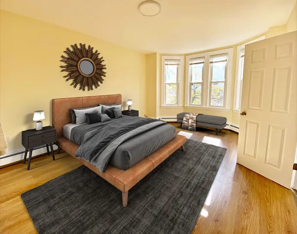 a spacious bedroom with a bed a couch and a potted plant with wooden floor