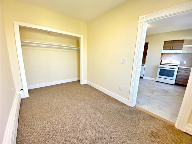 a view of an empty room and a kitchen