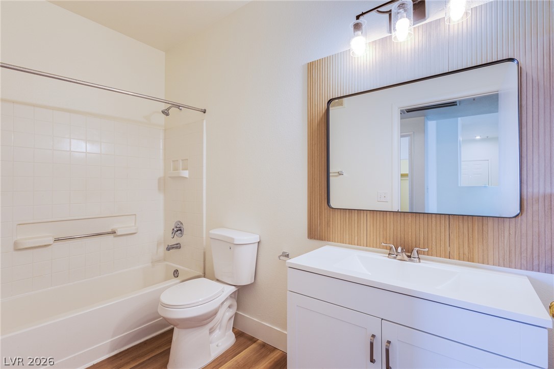 9050 West Warm Springs Road, Unit 1011 Las Vegas, NV 89148 - Photo 12 of 32 A well-lit bathroom features a single vanity with a mirror, a shower, and a toilet.