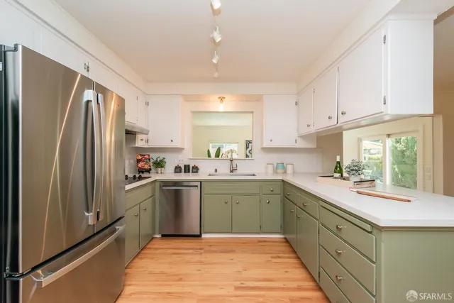 a kitchen with stainless steel appliances a dining table chairs and wooden floor