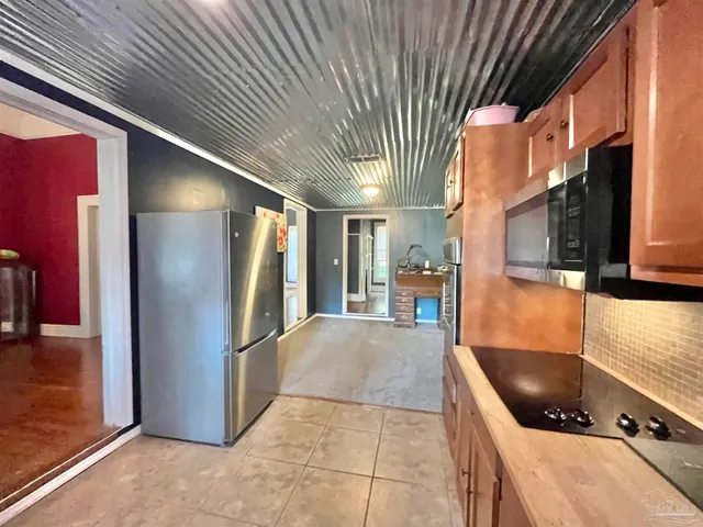 a kitchen with stainless steel appliances granite countertop a refrigerator a stove and a sink with wooden cabinets