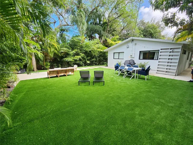 a front view of house with a garden and chairs