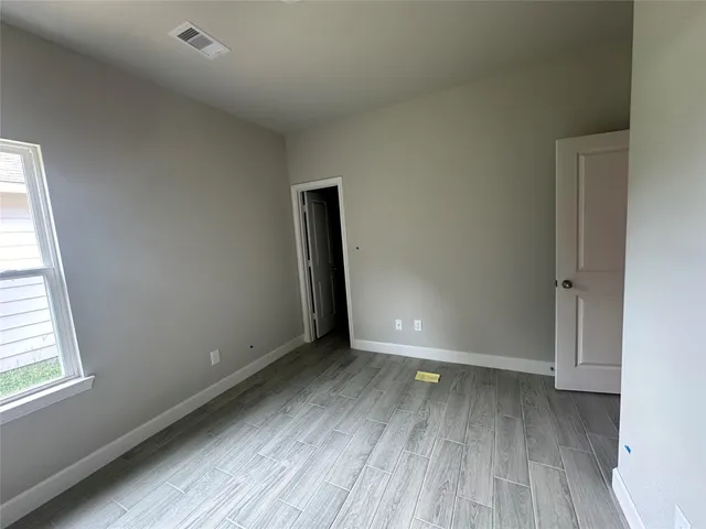 an empty room with wooden floor and windows