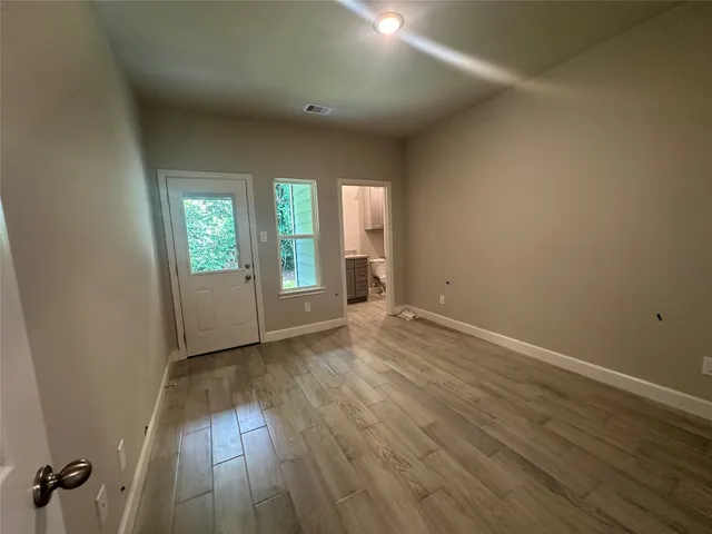 an empty room with wooden floor and windows