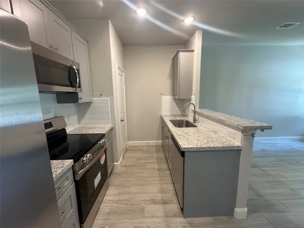 a kitchen with granite countertop sink stainless steel appliances and cabinets