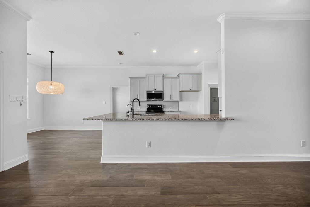 544 Gant Road Sherman, TX 75090 - Photo 7 of 39 Wood-finish flooring throughout, crown molding, kitchen with light gray cabinetry, built-in microwave, and a black faucet