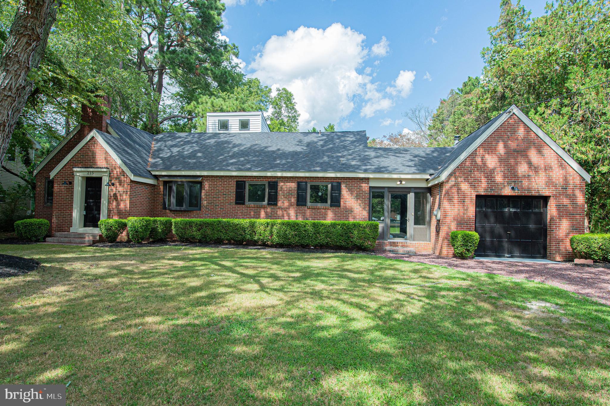 a front view of a house with a yard and trees