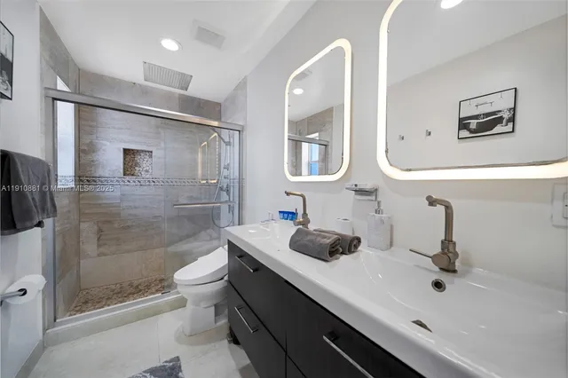 a bathroom with a double vanity sink toilet and shower