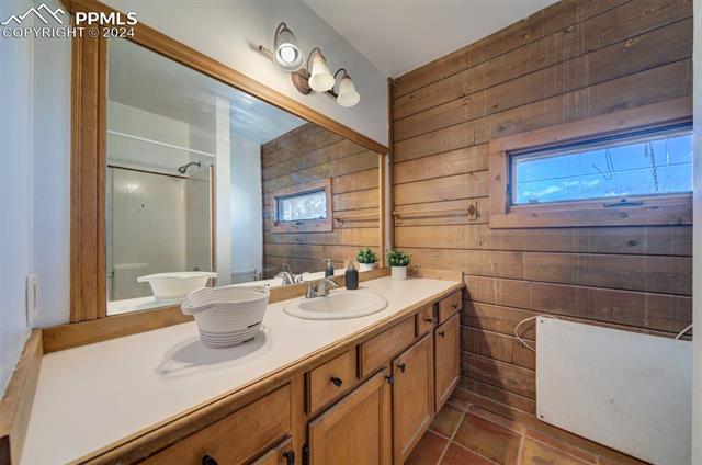 19350 Lemesany Road Calhan, CO 80808 - Photo 22 of 46 Bathroom with wood walls, vanity, and tile flooring, tub/shower combo