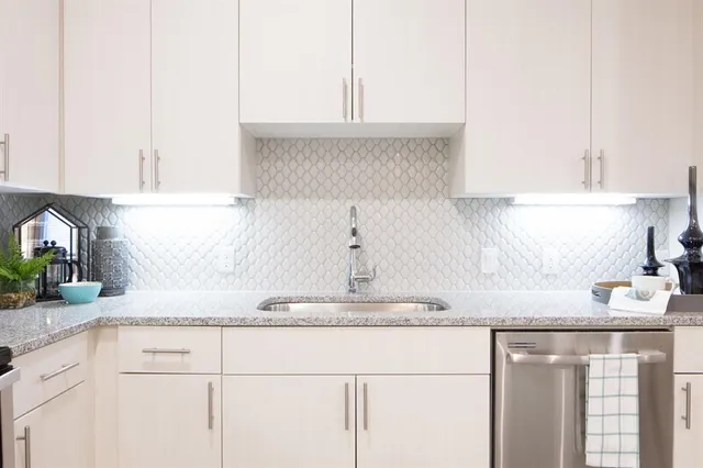 a kitchen with granite countertop white cabinets and a sink
