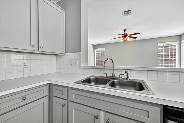 a kitchen with granite countertop a stove top oven a sink dishwasher and white cabinets with wooden floor