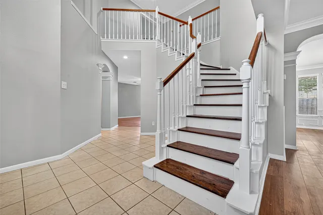 a view of an empty room with wooden floor and staircase