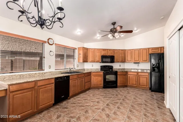 a large kitchen with kitchen island granite countertop a refrigerator a stove a sink a dining table and chairs with wooden floor