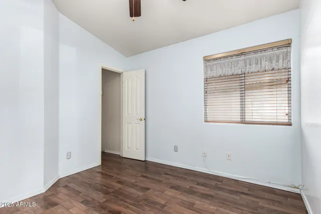 an empty room with wooden floor ceiling fan and window