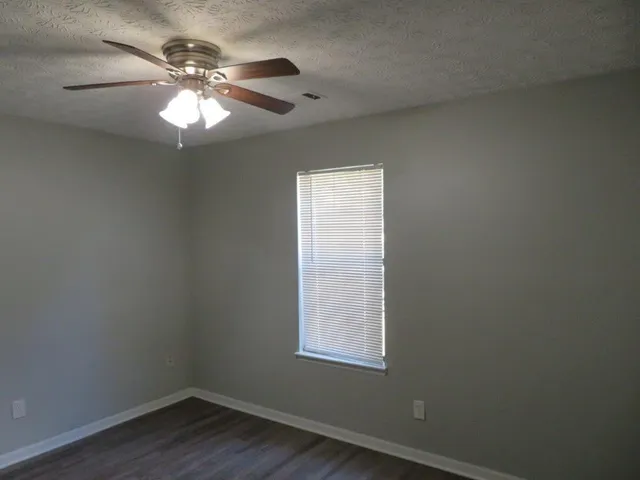 an empty room with wooden floor and chandelier fan