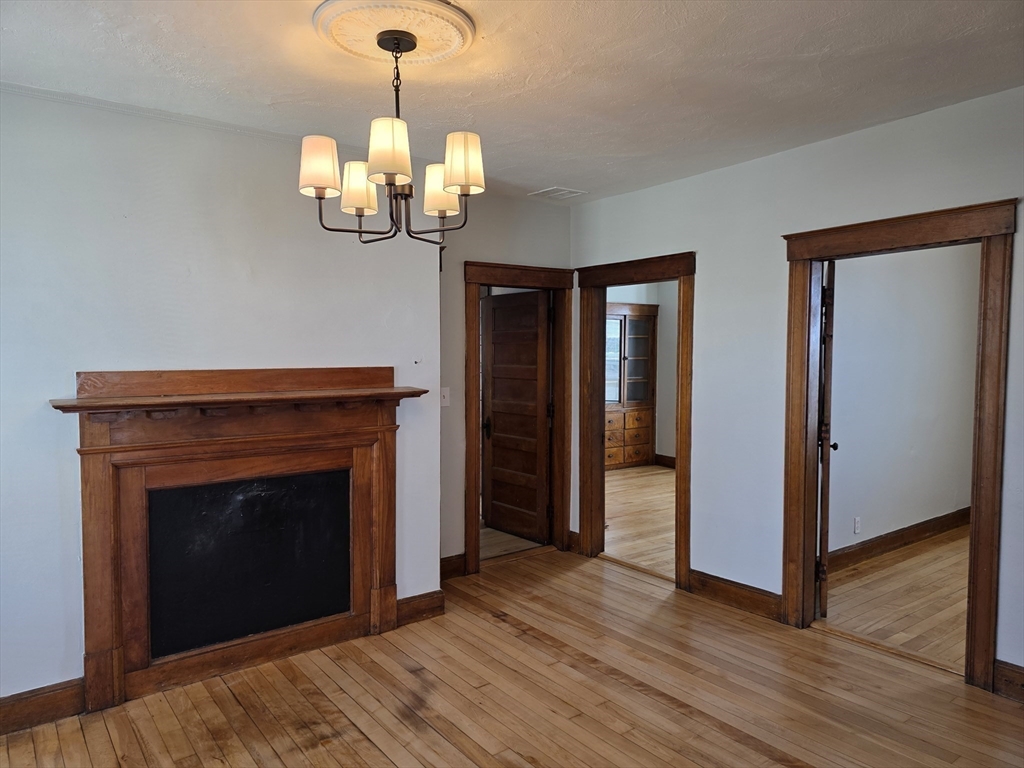 2 Hillside Street, Unit 3 Worcester, MA 01610 - Photo 22 of 30 a view of an empty room with wooden floor fireplace and a window