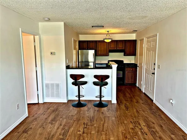 a view of a kitchen with kitchen island stainless steel appliances wooden floor and chair