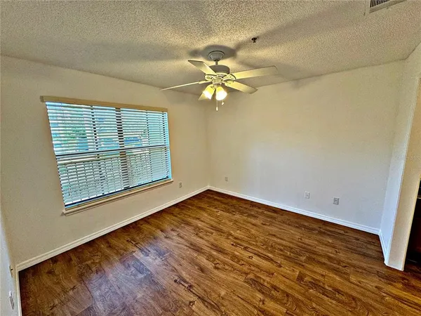 a view of an empty room with chandelier fan and wooden floor