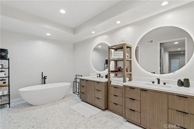 a spacious bathroom with a double vanity sink mirror and bathtub