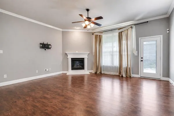 an empty room with wooden floor fireplace and windows