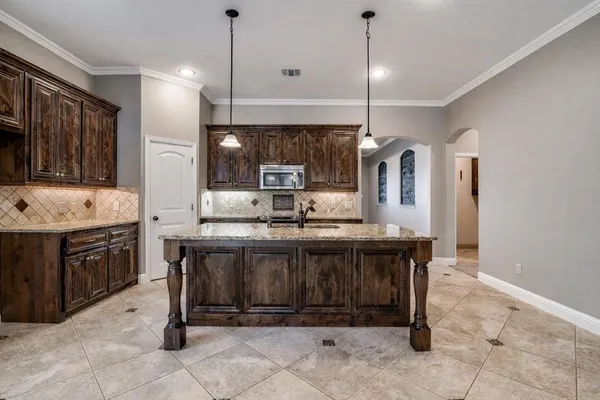 a kitchen with kitchen island granite countertop a stove a sink a oven and a refrigerator