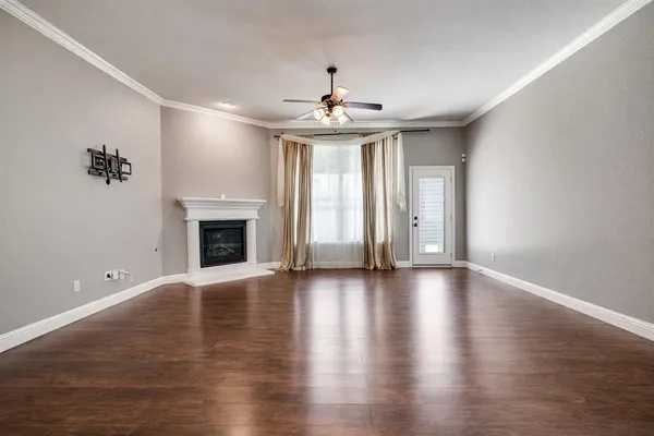 an empty room with wooden floor chandelier and windows