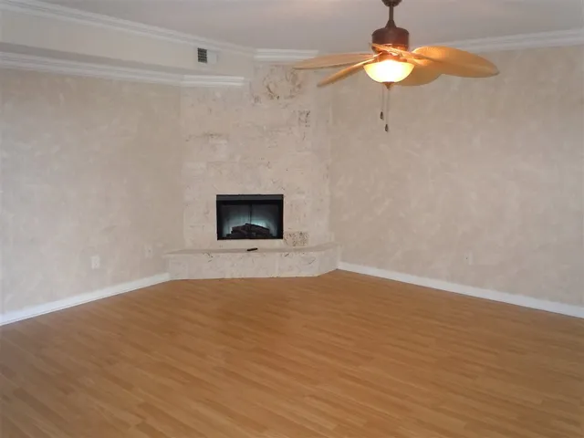 a view of empty room with a fireplace and wooden floor