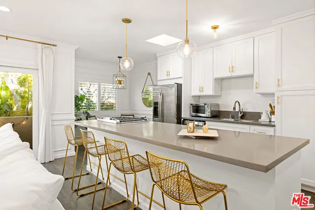 a kitchen with stainless steel appliances granite countertop a stove a refrigerator a sink a dining table and chairs with white cabinets