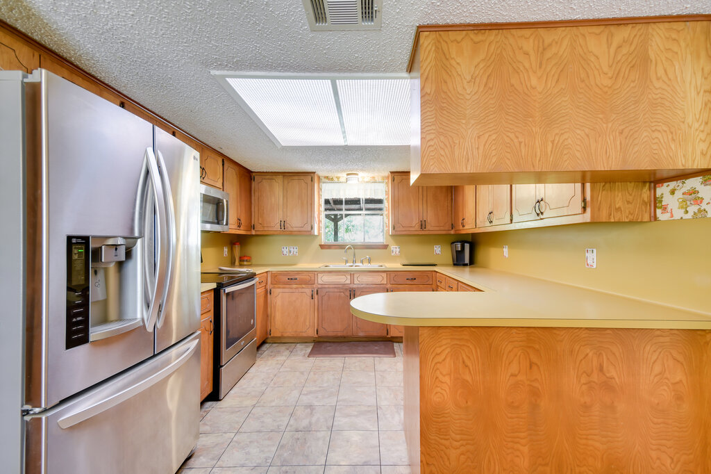 301 Navajo Trail Georgetown, TX 78633 - Photo 23 of 35 Kitchen featuring appliances with stainless steel finishes, a sink, a peninsula, light countertops, and a textured ceiling