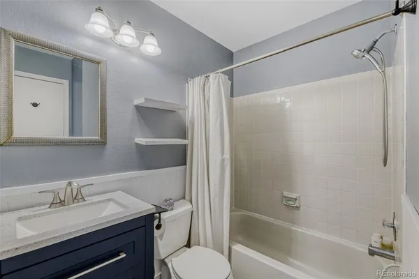 a bathroom with a granite countertop sink toilet a mirror and shower