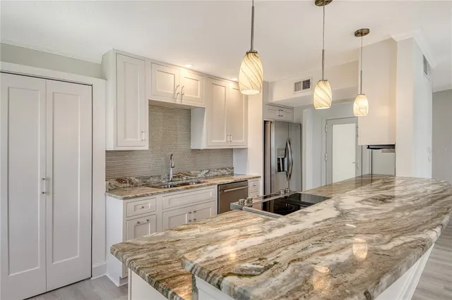 a kitchen with granite countertop a sink stainless steel appliances and cabinets