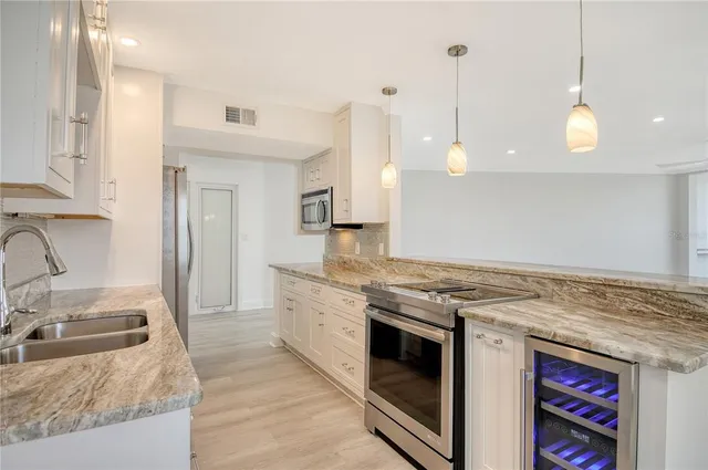 a kitchen with stainless steel appliances granite countertop a sink a stove and a refrigerator