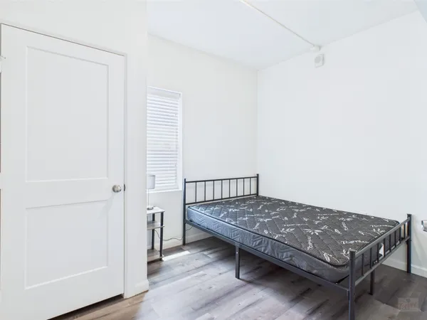 a view of a bedroom with a bed and wooden floor