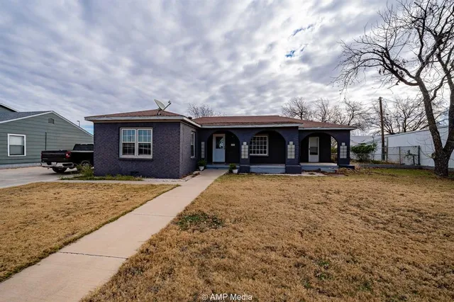 a view of a house with a barbeque and large trees