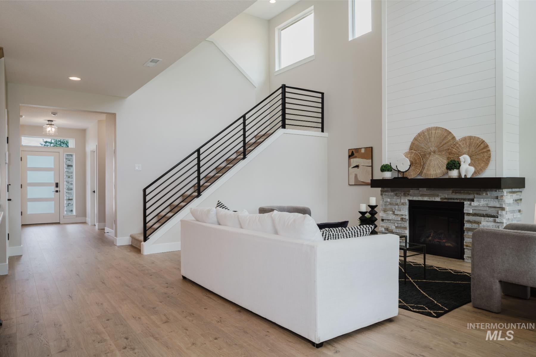 2866 North Stone Mill Avenue, Unit ROUGE Eagle, ID 83616 - Photo 8 of 18 Living room with stairway, light wood finished floors, a towering ceiling, a stone fireplace, and recessed lighting