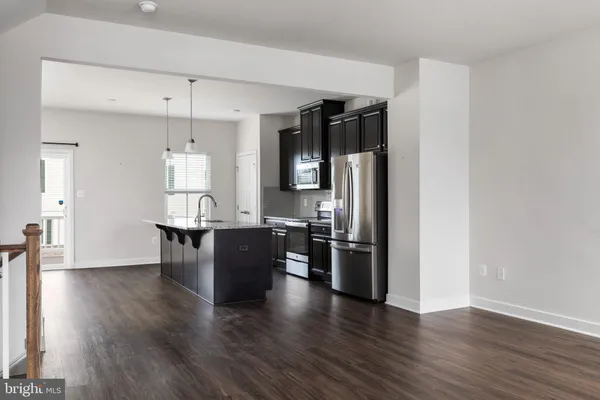 an open kitchen with wooden floor and refrigerator