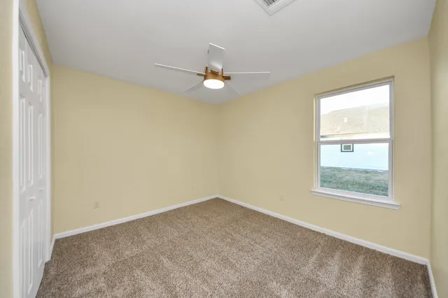 an empty room with a window and a ceiling fan