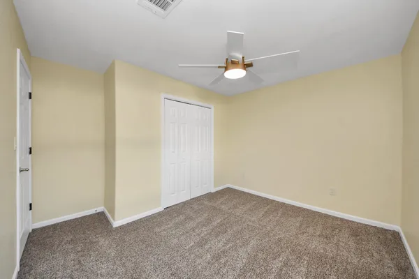 an empty room with a ceiling fan and a window