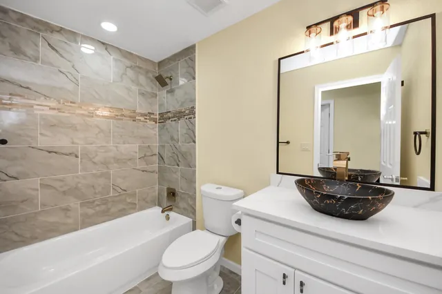 a bathroom with a sink a toilet a mirror a bathtub and shower