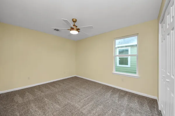 an empty room with a window and a ceiling fan