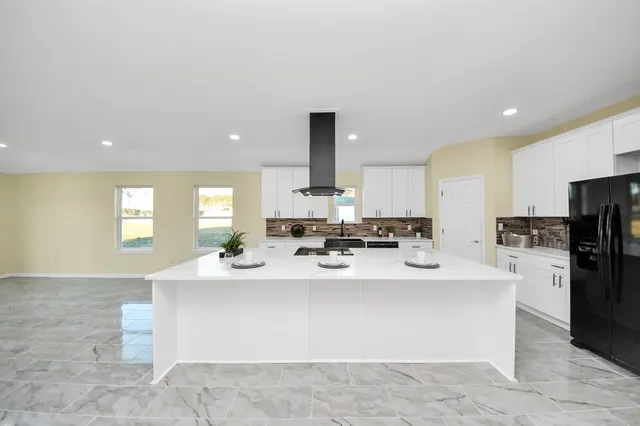 a large white kitchen with a large window and stainless steel appliances