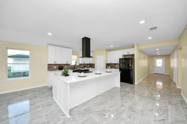 a large white kitchen with a large window and stainless steel appliances