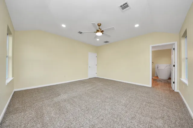 an empty room with windows and fan