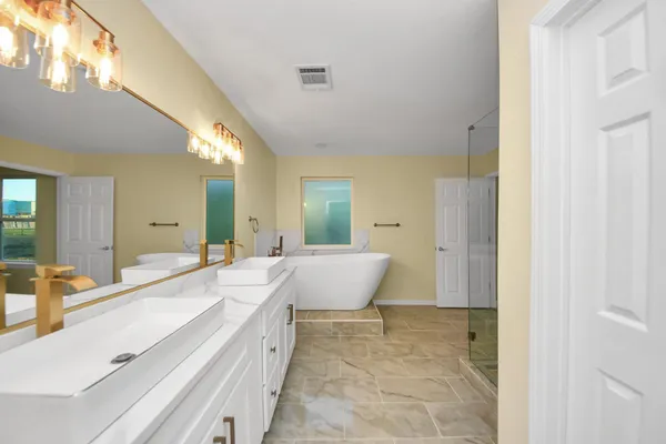 a spacious bathroom with a tub sink and mirror