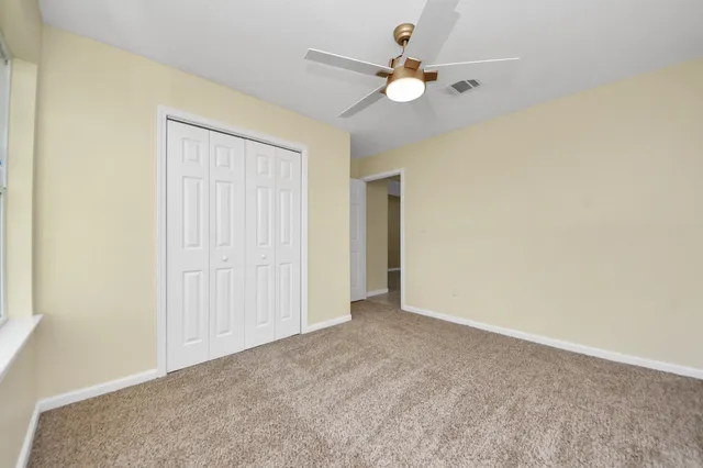 an empty room with a ceiling fan and a window