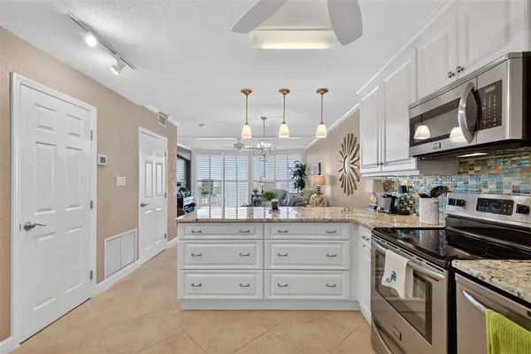 a kitchen with granite countertop white cabinets and stainless steel appliances