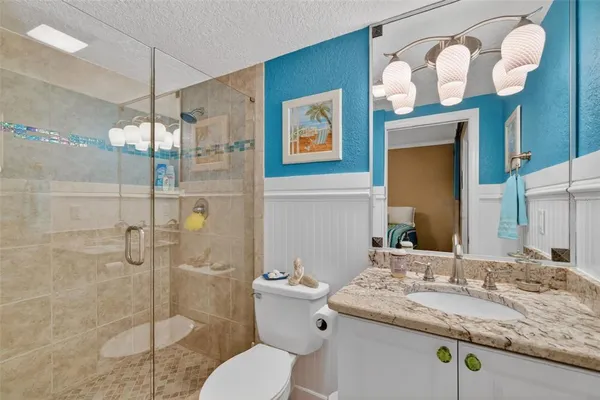 a bathroom with a granite countertop double vanity sink mirror and shower