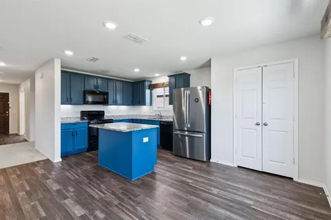 a kitchen with stainless steel appliances granite countertop a refrigerator and a wooden floors