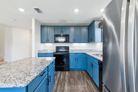 a kitchen with kitchen island granite countertop wooden cabinets a sink and a stove